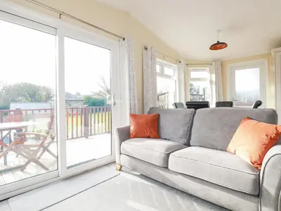 a living room with a couch and a sliding glass door at Laurel Lodge in Tintagel