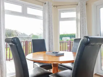 a dining room with a wooden table and chairs at Laurel Lodge in Tintagel
