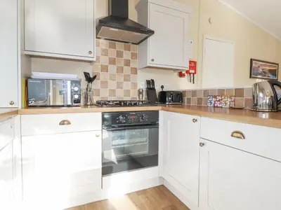 a kitchen with white cabinets and an oven at Laurel Lodge in Tintagel