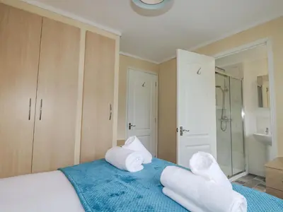 a bedroom with a blue bed with towels on it at Laurel Lodge in Tintagel
