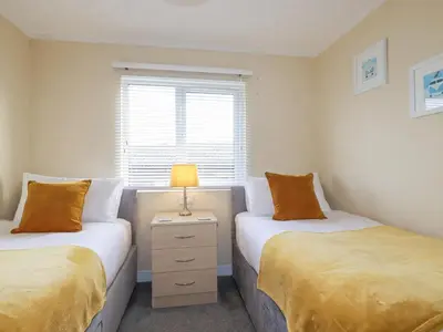 a bedroom with two beds and a lamp on a night stand at Laurel Lodge in Tintagel