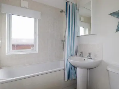 a bathroom with a sink and a tub and a window at Laurel Lodge in Tintagel
