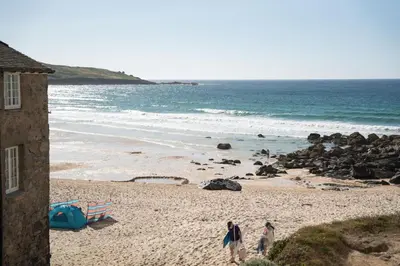 two people walking on a beach near the ocean at 3 St Nicholas Court in St Ives