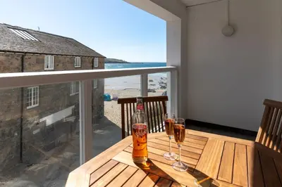 a table with two glasses of beer on a balcony at 3 St Nicholas Court in St Ives