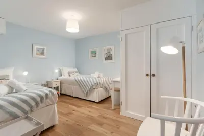 a bedroom with two beds and a chair and a desk at Four Seawinds in St Ives