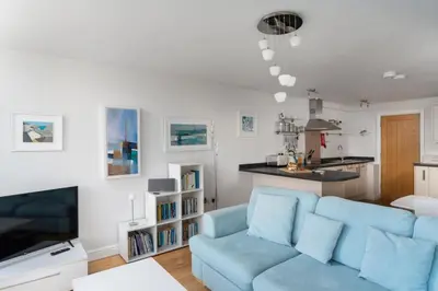 a living room with a blue couch and a kitchen at Four Seawinds in St Ives