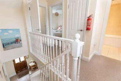 a white staircase in a home with a white stair case at The Oystercatcher in St Ives