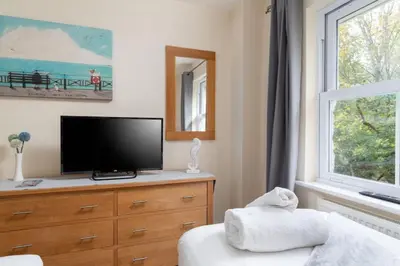 a living room with a tv on a dresser and a window at The Oystercatcher in St Ives