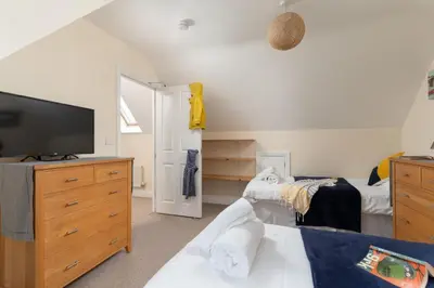a bedroom with a bed and a dresser with a television at The Oystercatcher in St Ives