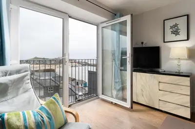 a living room with a balcony with a television at 10 Fernlea Court in St Ives