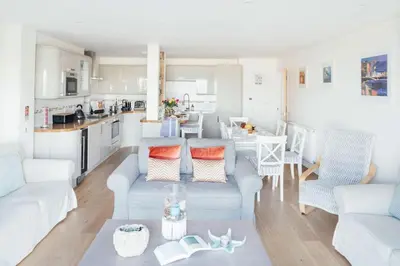 a living room with white furniture and a kitchen at 10 Fernlea Court in St Ives