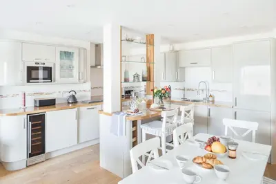 a kitchen with white cabinets and a table with food on it at 10 Fernlea Court in St Ives
