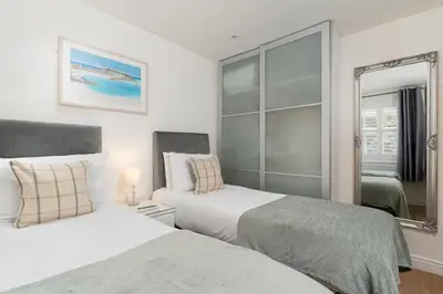 a bedroom with two beds and a mirror at 10 Fernlea Court in St Ives
