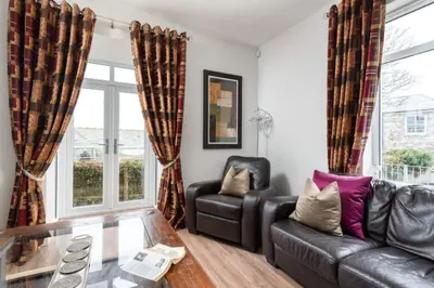 a living room with a leather couch and a glass table at 3 The Elms in St Ives