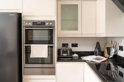 a kitchen with white cabinets and black appliances at 3 The Elms in St Ives