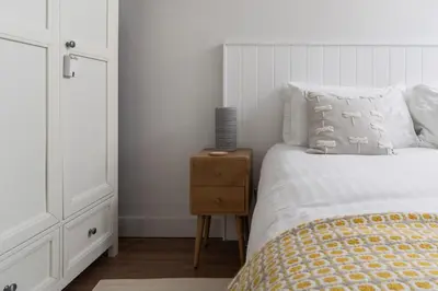 a white bedroom with a bed and a night stand at 11 Sunday School Court in St Ives