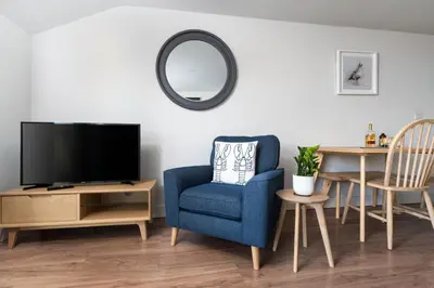 a living room with a blue chair and a tv at 11 Sunday School Court in St Ives