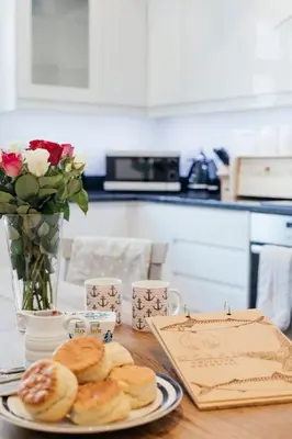 a table with a plate of pastries and a vase of roses at 2 The Elms in St Ives