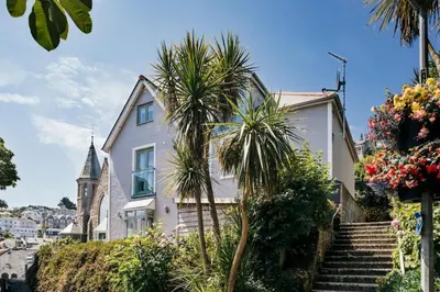 a white house with palm trees in front of it at 2 The Elms in St Ives