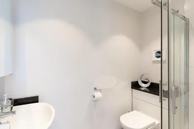 a bathroom with a toilet and a glass shower at 1 The Elms in St Ives