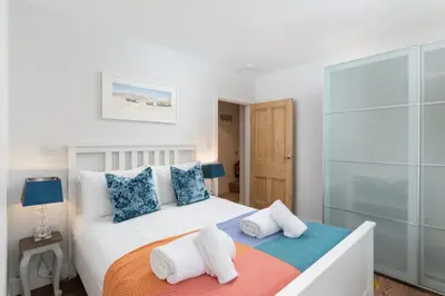 a bedroom with a large white bed with towels on it at 1 The Elms in St Ives