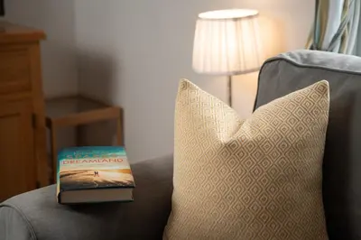 a book sitting on top of a couch with a pillow at 1 The Elms in St Ives