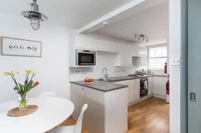a kitchen with white cabinets and a table and a table and chairs at 22 Piazza in St Ives
