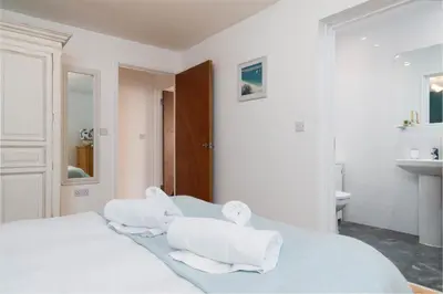 a white bedroom with two towels on a bed at The Beach in Praa Sands
