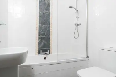 a white bathroom with a shower and a sink at The Beach in Praa Sands
