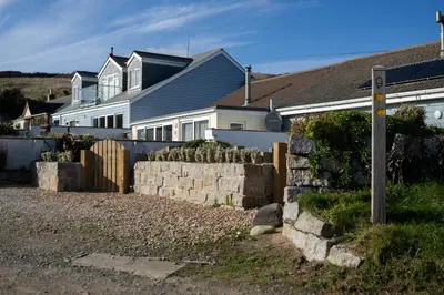 a white house with a fence in front of it at The Beach in Praa Sands