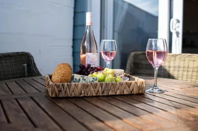 a tray of food and wine glasses on a wooden table at The Beach in Praa Sands