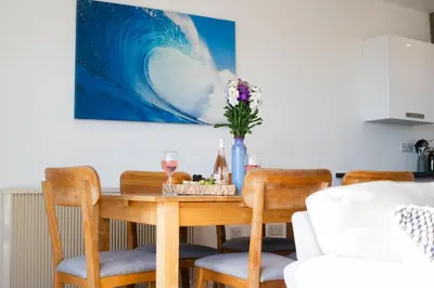 a dining room table with chairs and a painting on the wall at The Beach in Praa Sands