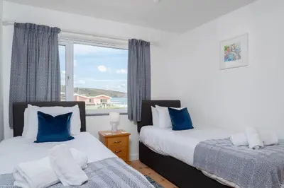 two beds in a room with a window at The Rockpool in Praa Sands