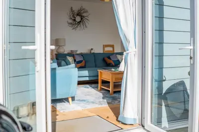 a living room with a blue couch and a table at The Rockpool in Praa Sands