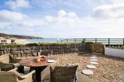 a patio with a table and chairs and the ocean at The Rockpool in Praa Sands
