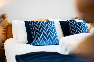 a bed with blue and white pillows on it at The Rockpool in Praa Sands