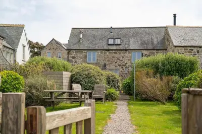 a garden with a wooden fence and a table and benches at Rosewall Cottage in St Ives