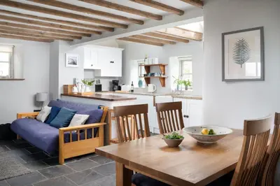 a kitchen and a living room with a table and a couch at Rosewall Cottage in St Ives