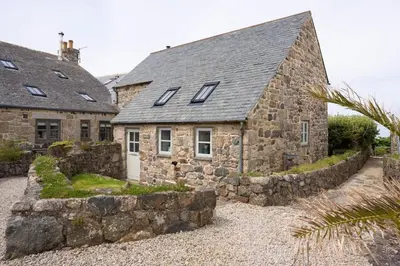 an old stone house with a stone wall at Rosewall Cottage in St Ives