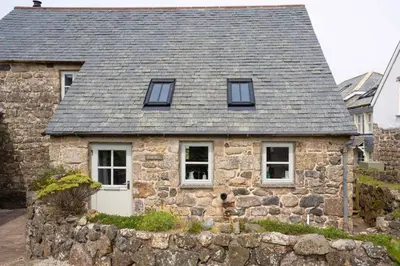 a stone house with a gray roof and windows at Rosewall Cottage in St Ives