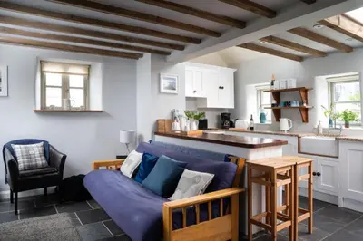 a living room with a blue couch and a kitchen at Rosewall Cottage in St Ives
