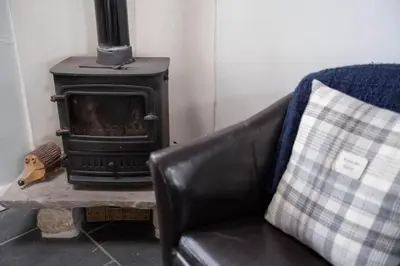 a leather couch with a stove in a living room at Rosewall Cottage in St Ives