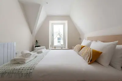 a bedroom with a large white bed with a window at Skylar in St Ives