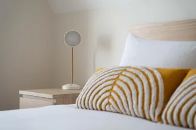 a bed with a yellow and white striped pillow and a lamp at Skylar in St Ives