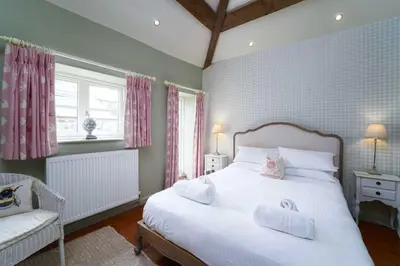a bedroom with a large white bed and a chair at Upper Trowan in St Ives