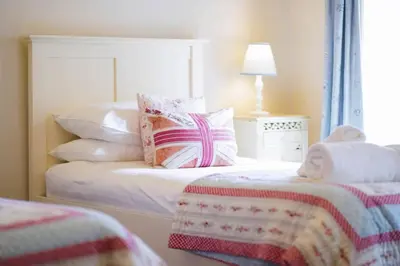 a bedroom with a bed with a white headboard and pillows at Upper Trowan in St Ives