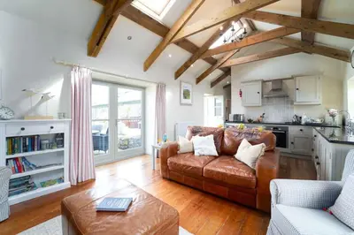a living room with a brown couch and a kitchen at Upper Trowan in St Ives