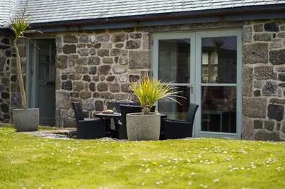 a patio with a table and chairs in front of a building at Upper Trowan in St Ives