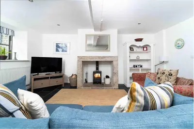 a living room with a blue couch and a fireplace at Quick's Cottage in St Ives