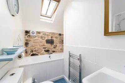 a bathroom with a tub and a toilet and a sink at Quick's Cottage in St Ives
